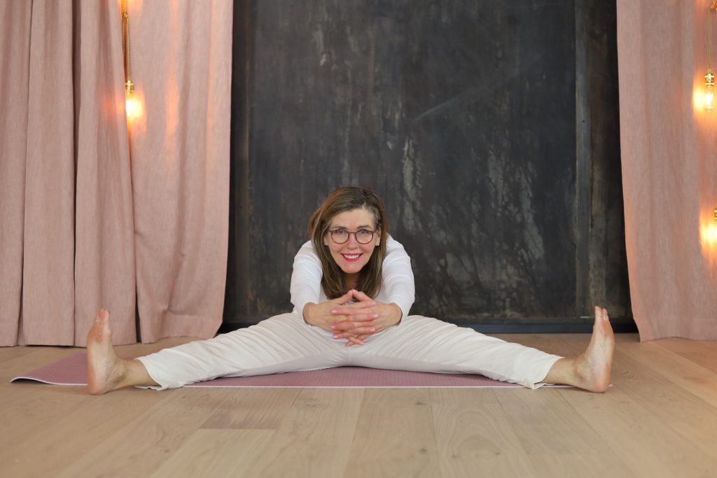 Eva Aminoff making a yoga pose on the mat, looking into the camera
