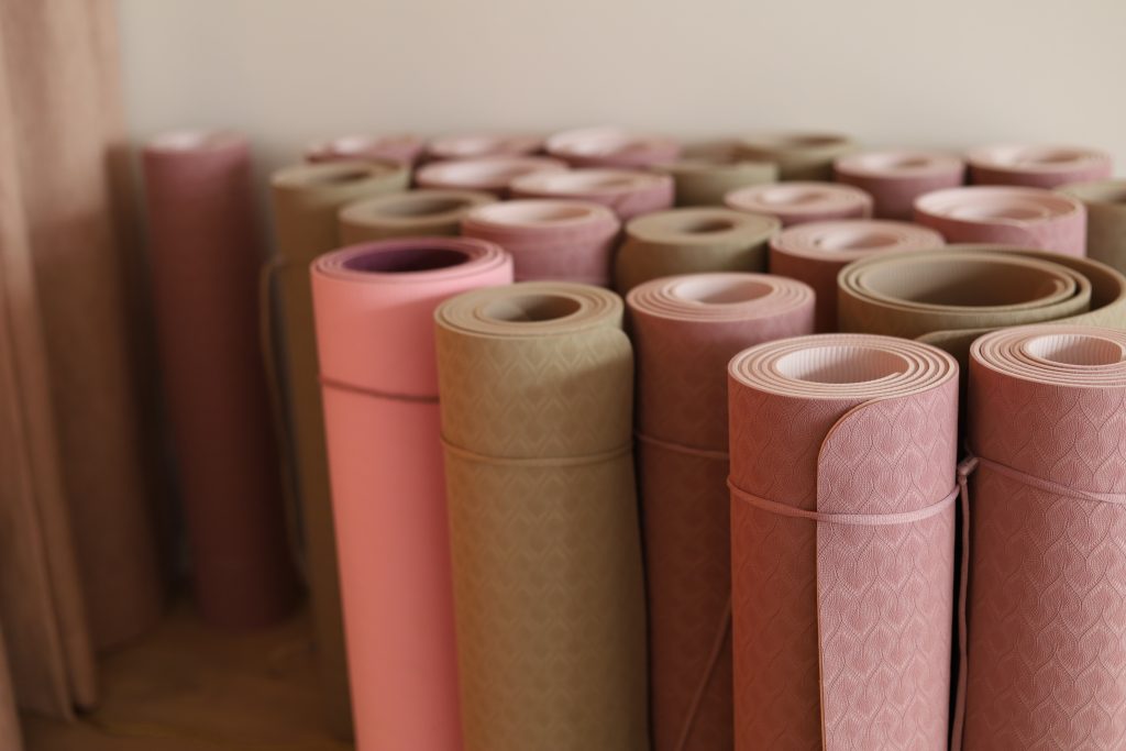 Pink and beige jooga mats standing upright against the wall